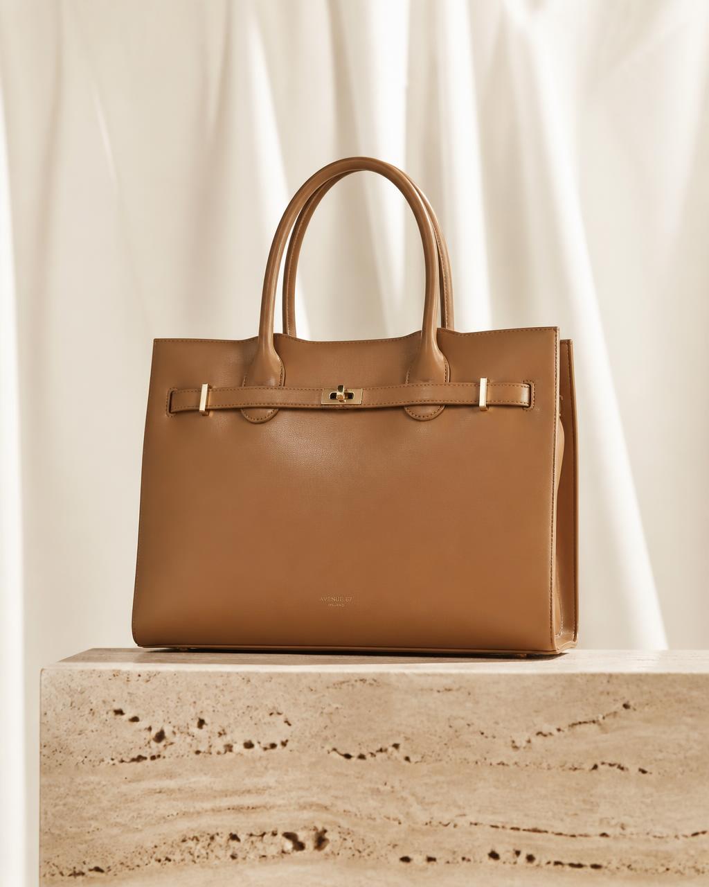 Tan calfskin structured tote bag on a travertine plinth